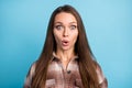 Portrait of young shocked amazed surprised speechless woman with long brown hair isolated on blue color background