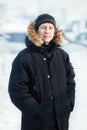 Portrait of a young Siberian man in cold winter day, wearing warm down jacket with fur hood, vertical. Snow, frost Royalty Free Stock Photo