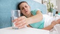 Portrait of young sick woman lying in bed and drinking pill Royalty Free Stock Photo