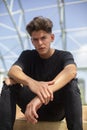 Portrait of young skateboarder with black t-shirt and street and blue sky background