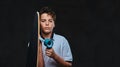 Portrait of a young skater boy dressed in a white t-shirt holds a longboard. on the dark background. Royalty Free Stock Photo