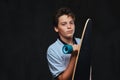 Portrait of a young skater boy dressed in a white t-shirt holds a longboard. Isolated on the dark background. Royalty Free Stock Photo