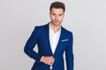 Portrait of young smart casual man buttoning his blue suit