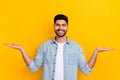 Portrait of young smart guy hold two hands comparison measurement prices isolated on yellow color background