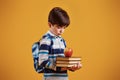 Portrait of young smart schooler in the studio against yellow background