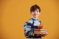 Portrait of young smart schooler in the studio against yellow background