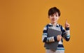 Portrait of young smart schooler in the studio against yellow background