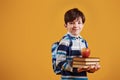 Portrait of young smart schooler in the studio against yellow background