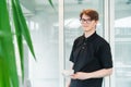 Portrait of young smiling affable waiter carrying on coffee cup to client table in cafe. Hospitality service job Royalty Free Stock Photo