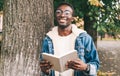 Portrait young smiling african man student with a book looking away wearing an eyeglasses in autumn city park Royalty Free Stock Photo