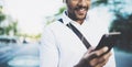 Portrait of young smiling african man using smartphone hands while standing at sunny city street.Concept of happy Royalty Free Stock Photo