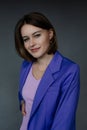 Portrait of young smiling amazing blue-eyed woman businesswoman holding hand on waist, posing on grey background. Royalty Free Stock Photo