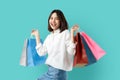 Portrait of young smiling asian woman casual clothes holding multicolored shopping bags on light blue background. Royalty Free Stock Photo