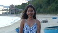 Portrait of a young and smiling Asian woman in a summer dress at the beach.