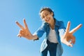 Portrait of a young smiling attractive woman in jeans clothes at sunny day on the blue sky background. woman shows a Royalty Free Stock Photo