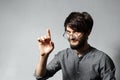 Portrait of young smiling bearded guy with disheveled hair, wearing grey shirt and glasses. Pointing up with his finger. Royalty Free Stock Photo