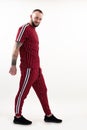 Portrait of young smiling bearded man with short dark hair wearing red striped sport wear, standing on white background. Royalty Free Stock Photo