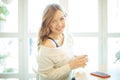 Portrait of young smiling beautiful curvy blond hair woman sitting at the table with cup of tea Royalty Free Stock Photo