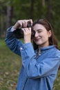 Portrait of a young smiling beautiful woman freelancer in an autumn park with a camera. Girl takes photos for social Royalty Free Stock Photo