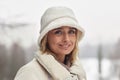 Portrait of young smiling blond woman in white winter hat and coat Royalty Free Stock Photo