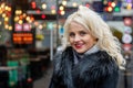 Portrait of a young smiling blonde woman against the background of defocused holiday lights. The concept of Christmas time. Copy Royalty Free Stock Photo