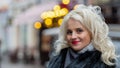 Portrait of a young smiling blonde woman on defocused street background. Copy space Royalty Free Stock Photo