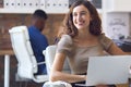 Portrait Of Young Smiling Businesswoman Working On Laptop At Desk In Office Royalty Free Stock Photo