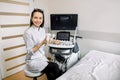Portrait of young smiling Caucasian woman doctor, 4D ultrasound scanning machine operator, holding ultrasound scanner Royalty Free Stock Photo