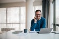 Portrait of young smiling cheerful entrepreneur in casual office making phone call while working