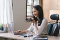 Portrait of a young, smiling, and cheerful entrepreneur working in a casual office, effortlessly multitasking by making Royalty Free Stock Photo