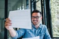 Portrait of young smiling cheerful man entrepreneur or businessman in casual office working with charts and graphs looking at Royalty Free Stock Photo