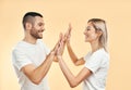 Portrait of young smiling couple giving high five to each other over studio background Royalty Free Stock Photo