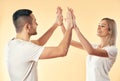 Portrait of young smiling couple giving high five to each other over studio background Royalty Free Stock Photo