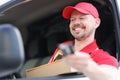 Portrait of young smiling courier driver in car window with box in hand Royalty Free Stock Photo