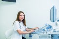 Portrait of young smiling doctor, ultrasound specialist looking at camera and using Ultrasound Scanning Machine for pacient Royalty Free Stock Photo