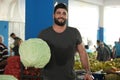 Portrait of young smiling farmer holding big cabbage head.