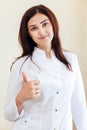 Young smiling female brunette Doctor-cosmetologist shows thumb near the window in the cosmetology office Royalty Free Stock Photo