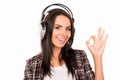 Portrait of young smiling girl with head-phones listening music and gesturing ``OK Royalty Free Stock Photo