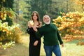 Portrait of young smiling girl sitting with grandfather against autumn park. Family lifestyle concept.