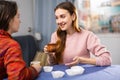 Portrait of young smiling girlfriends having fun together during drinking tea at table at home Royalty Free Stock Photo