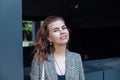 Portrait of young smiling slim green-eyed woman businesswoman standing near modern building outside, looking at camera.