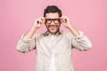 Portrait of young smiling handsome business man in casual shirt isolated on pink background touching his glasses Royalty Free Stock Photo