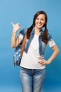 Portrait of young smiling joyful happy woman student in white t-shirt, denim clothes with backpack pointing thumb aside Royalty Free Stock Photo