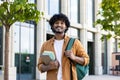 Portrait of a young smiling male Indian student standing outside the university with books in his hands. He goes to a Royalty Free Stock Photo