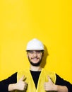 Portrait of young smiling man, builder engineer, showing thumbs up, wearing safety helmet for construction, glasses. Royalty Free Stock Photo