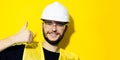 Portrait of young smiling man, builder engineer, showing thumbs up, wearing white construction safety helmet, glasses and jacket. Royalty Free Stock Photo