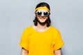 Portrait of young smiling man in yellow wearing sunglasses on textured background of grey. Royalty Free Stock Photo