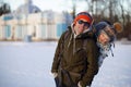 Portrait smiling man with little child in baby carrier backpack. Smiling happy family. Background of snowy winter park Royalty Free Stock Photo