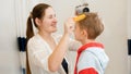 Portrait of young smiling mother drying and brushing wet hair of her little son after washing in bath. Concept of child Royalty Free Stock Photo