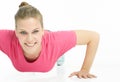 Portrait of a young smiling sports girl doing push ups isolated on a white background. Royalty Free Stock Photo